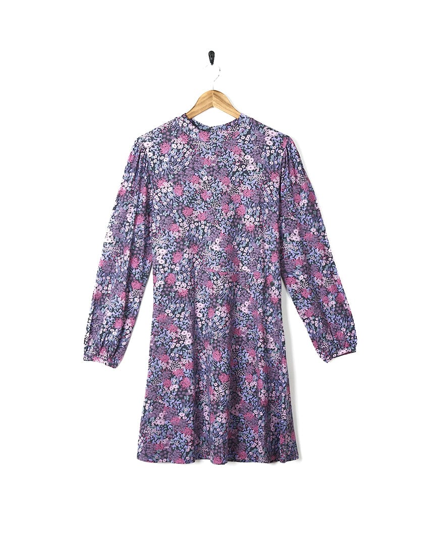A Saltrock Ramona Womens Mock Jersey Dress - Purple in a purple and pink print hanging on a wooden hanger.