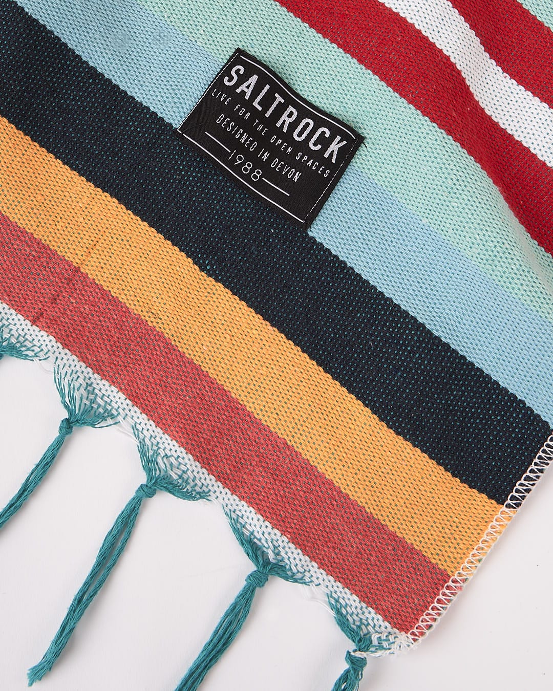 A colorful striped towel made from recycled cotton fiber with a woven label that says Saltrock.
