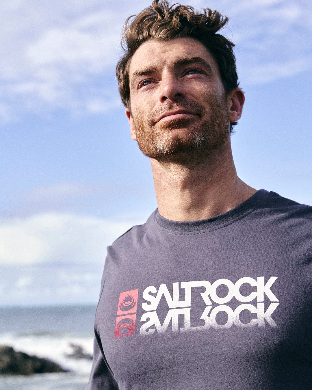 A man wearing a Reflect - Mens Long Sleeve T-Shirt - Grey with the Saltrock branding on it.