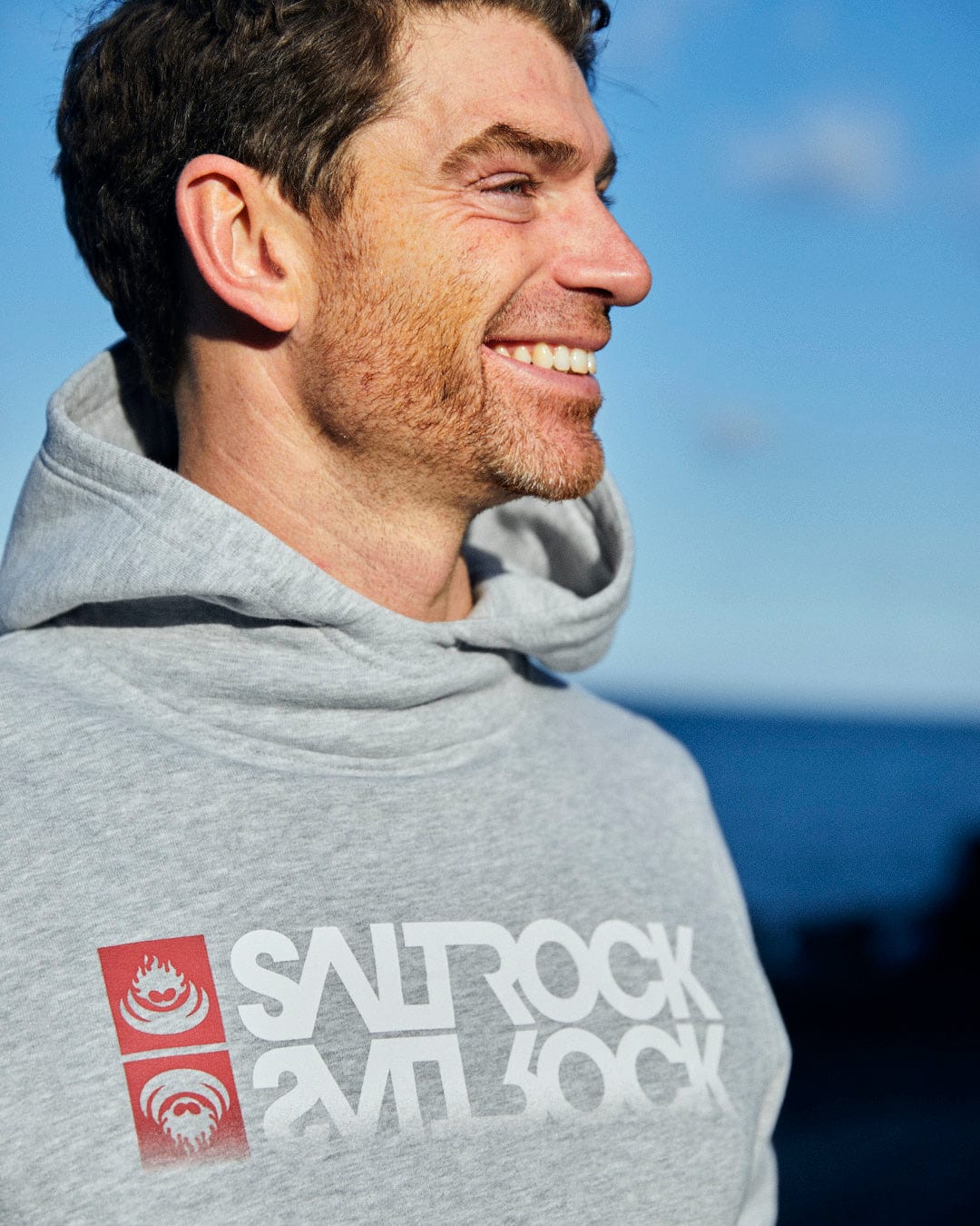 A man wearing the Reflect - Mens Pop Hoodie - Grey with the Saltrock branding.