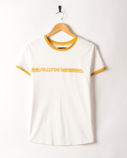 White Retro Ribbon - Womens Shorts Sleeve T-Shirt with yellow trim and "Saltrock" branding, hanging on a hook against a white wall.