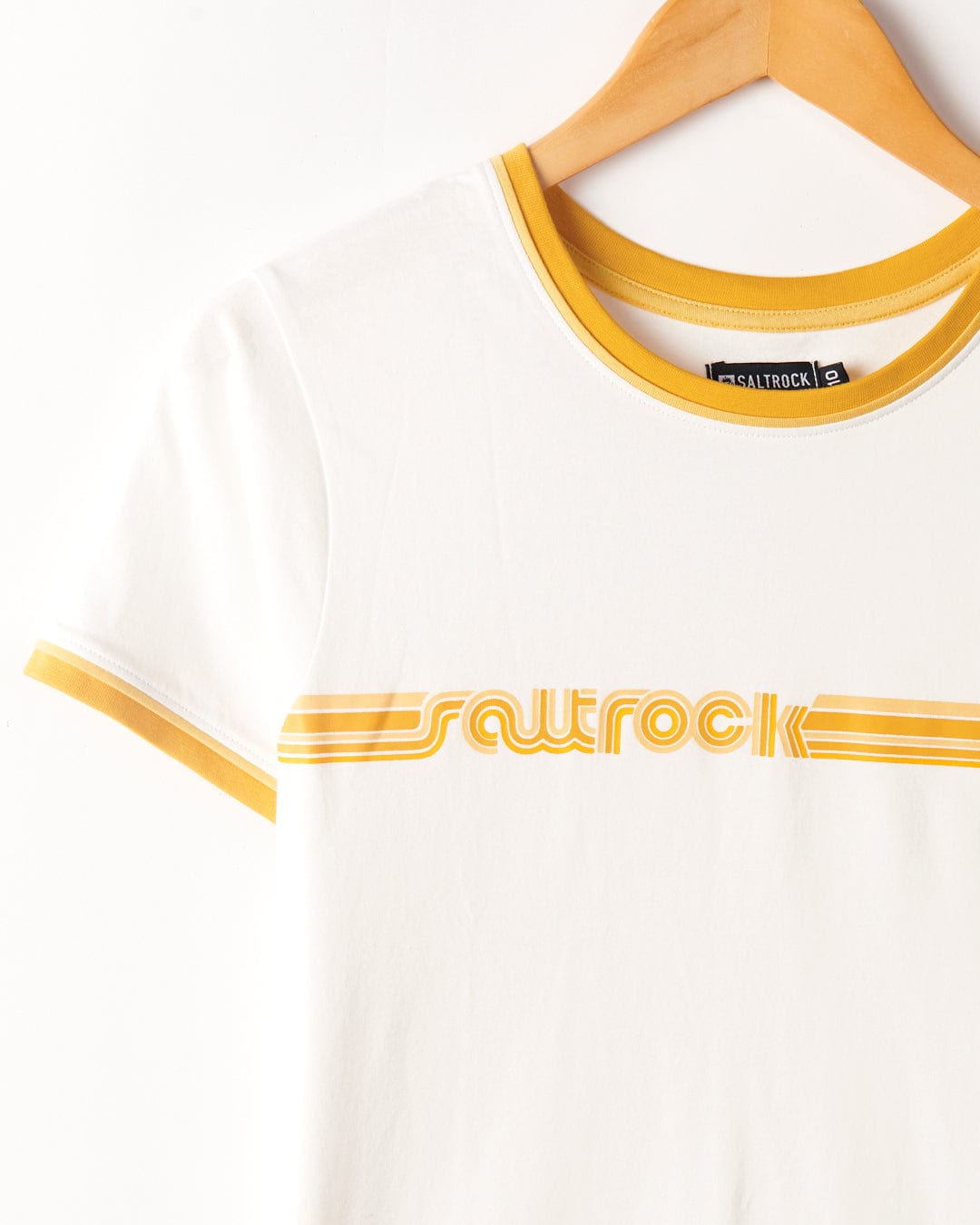 Saltrock's Retro Ribbon - Womens Shorts Sleeve T-Shirt in White with retro stripes and the word "squrock" printed across the chest, hanging on a wooden hanger against a white background.