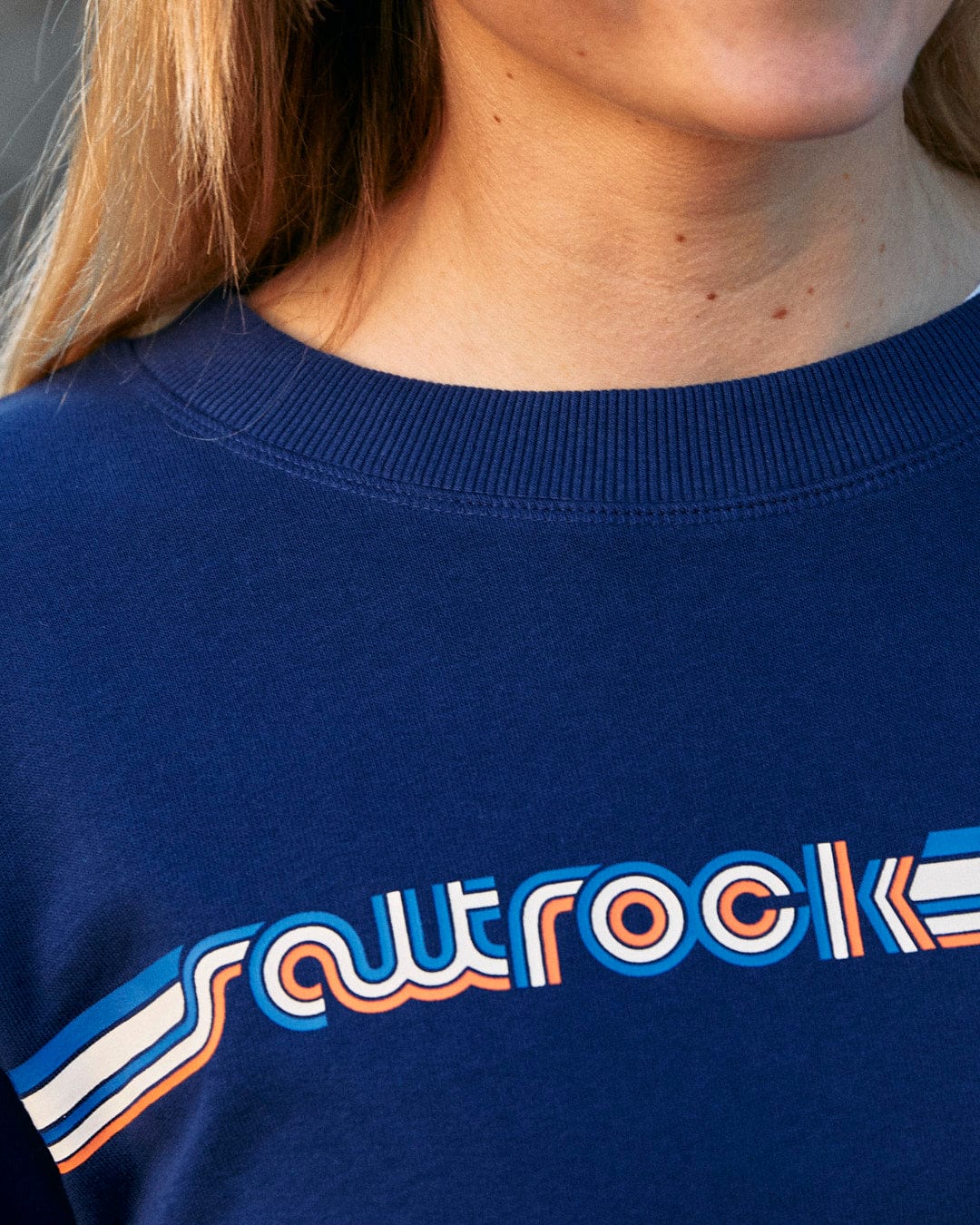 A woman wearing a Retro Ribbon - Womens Sweat - Blue sweatshirt with the Saltrock branding on it.