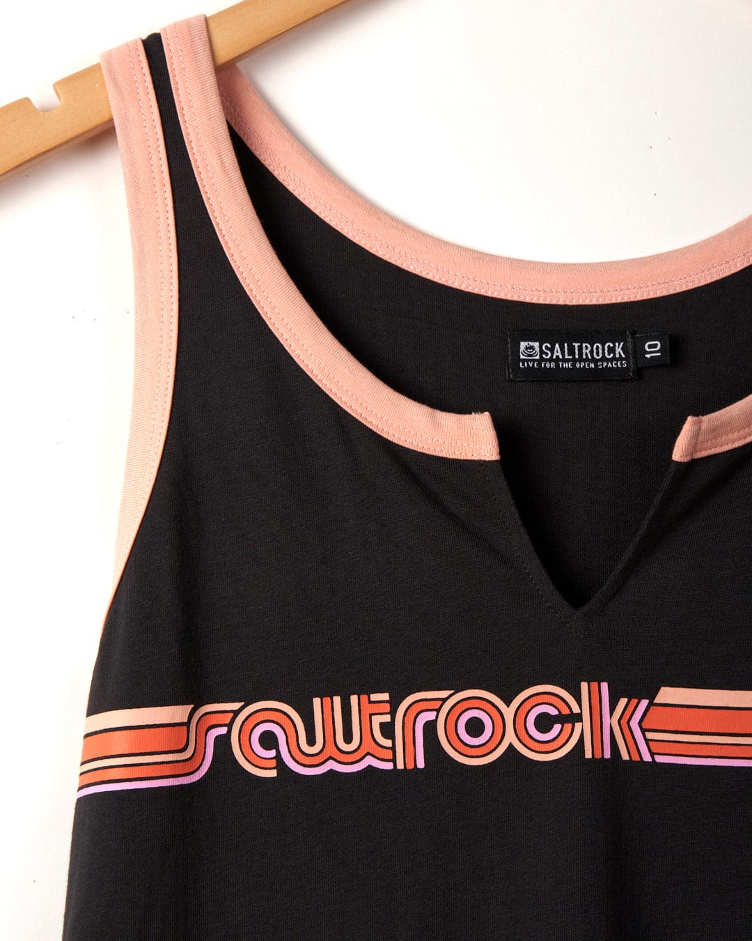 Retro Ribbon - Womens Vest - Dark Grey tank top with pink trim hanging on a wooden hanger, featuring the Saltrock logo in pink and orange on the chest, made from 100% cotton.