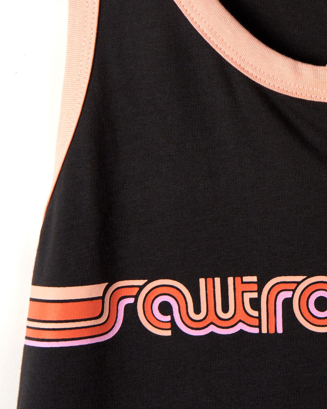 Close-up of a black fabric with the word "Saltrock" in stylized orange and pink lettering along the hem, featuring a Retro Ribbon - Womens Vest - Dark Grey stripe.