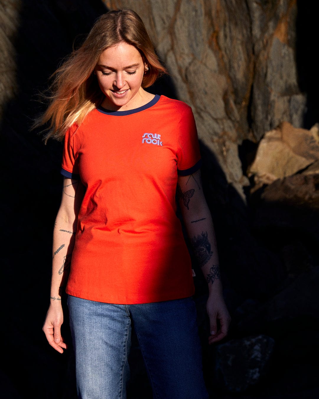 A woman sporting a stylish Saltrock Retro Wave Mini - Womens Short Sleeve T-Shirt - Red, complemented by a casual pair of jeans.