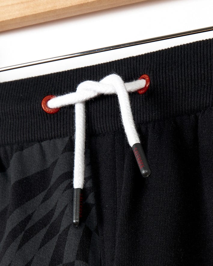 A stylish pair of Saltrock Rip It - Kids Jogging Bottom - Black jogger sweatpants with a red drawstring.