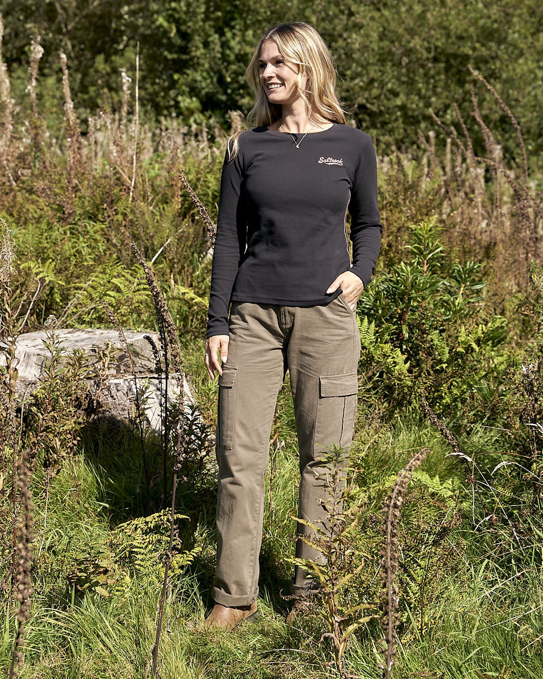 A woman standing in a field wearing a Saltrock - Rory Womens Long Sleeve Waffle T-Shirt - Black and cargo pants.