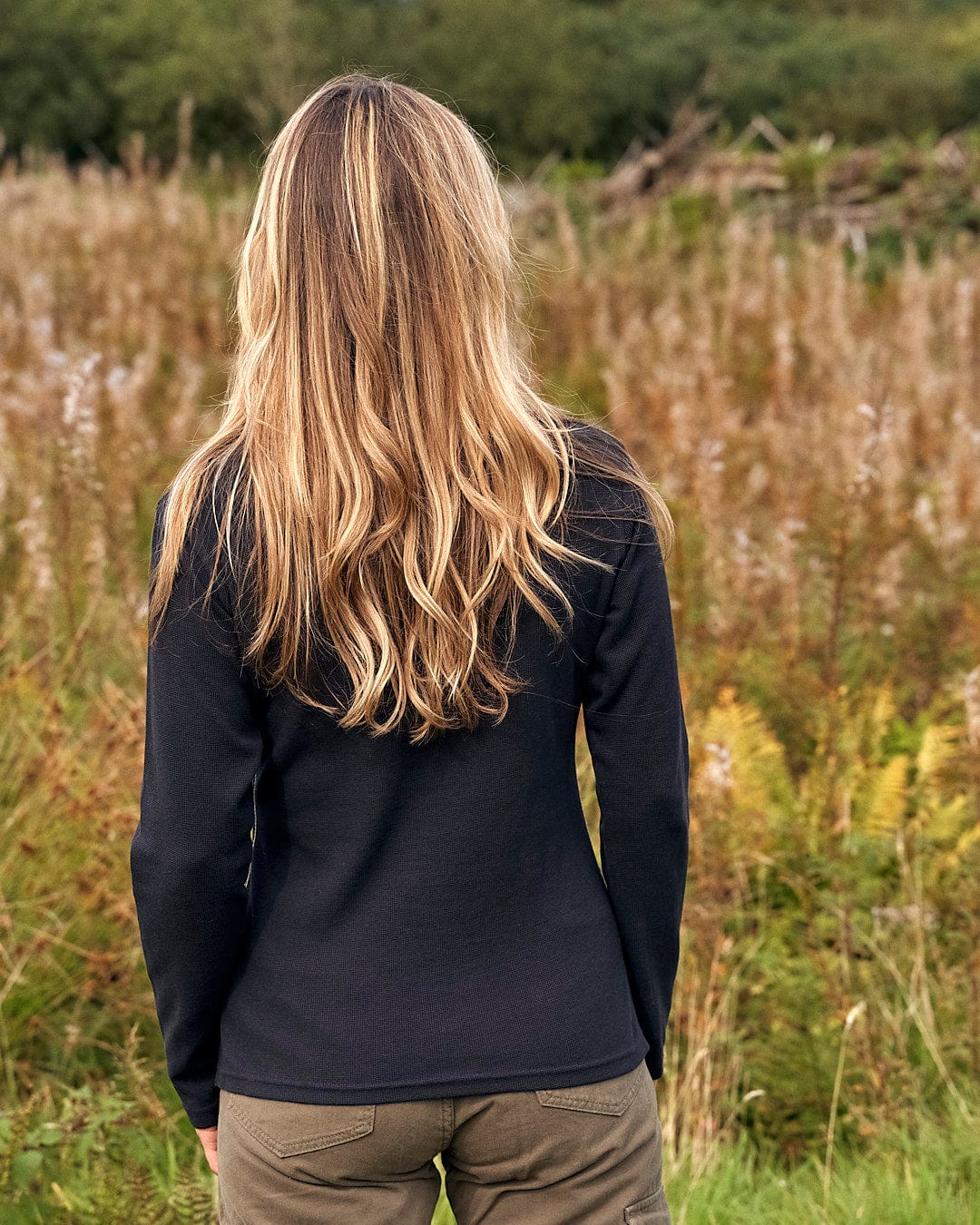 A woman is standing in a field wearing a Saltrock Rory - Womens Long Sleeve Waffle T-Shirt - Black.
