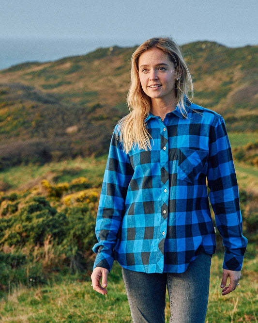 A woman wearing a Saltrock Rosalin - Womens Check Shirt - Blue/Black standing in a field.