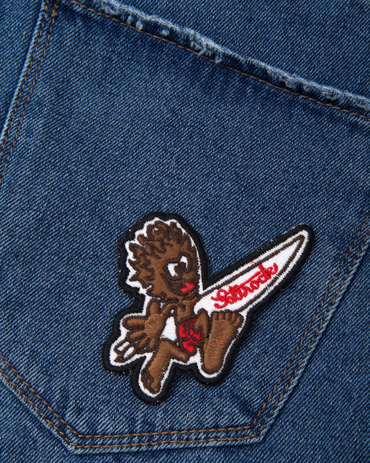 A blue denim pocket with a teddy bear embroidered on it, embellished with a Saltrock Running Man - Patches - Brown iron-on patch.