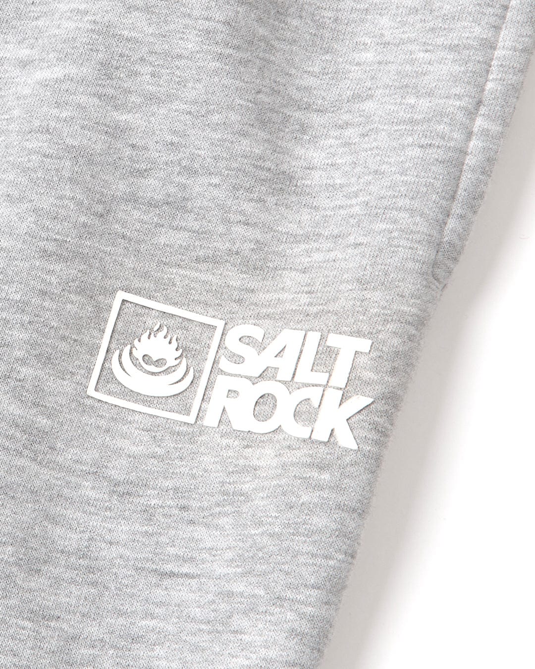 A close-up of a grey fabric with a Saltrock Original - Mens Joggers - Grey logo and a stylized flame above it.