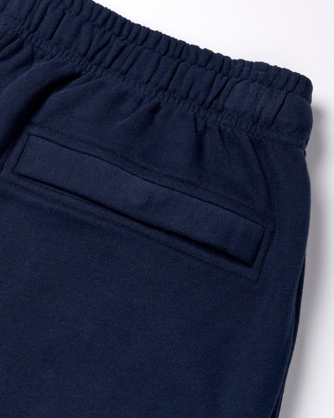 Close-up of a Saltrock Original - Mens Joggers - Dark Blue waistband with a back pocket detail and peach fluff lining.