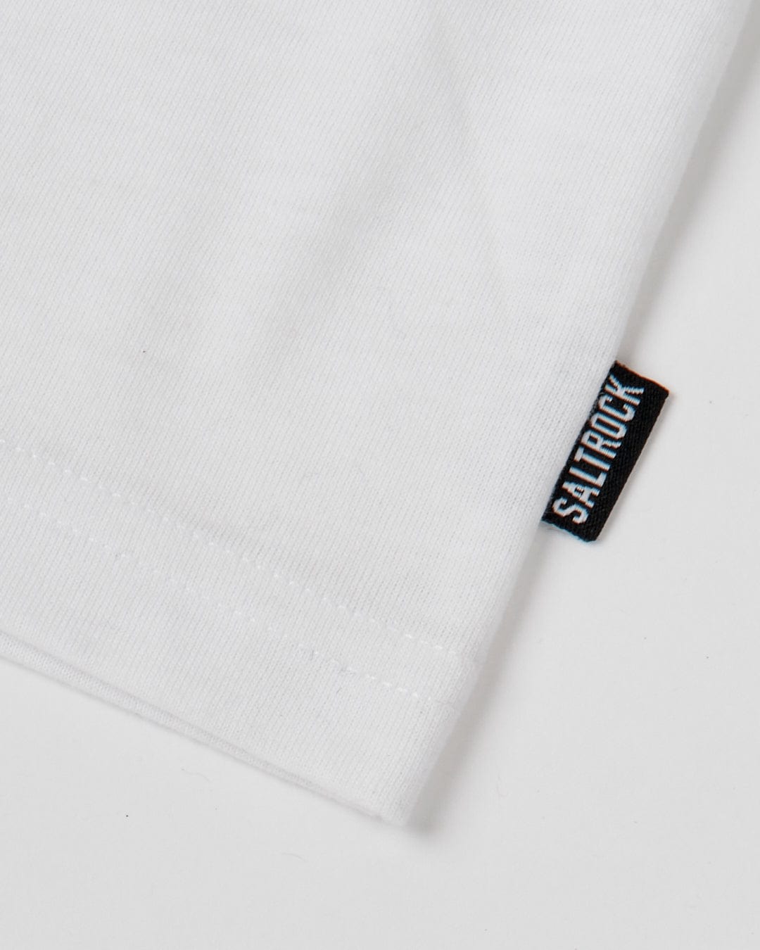 A close-up image of a Saltrock Original - Mens Short Sleeve T-Shirt in white fabric with a visible crew neckline and a small black label with the word "Saturday" in white letters.