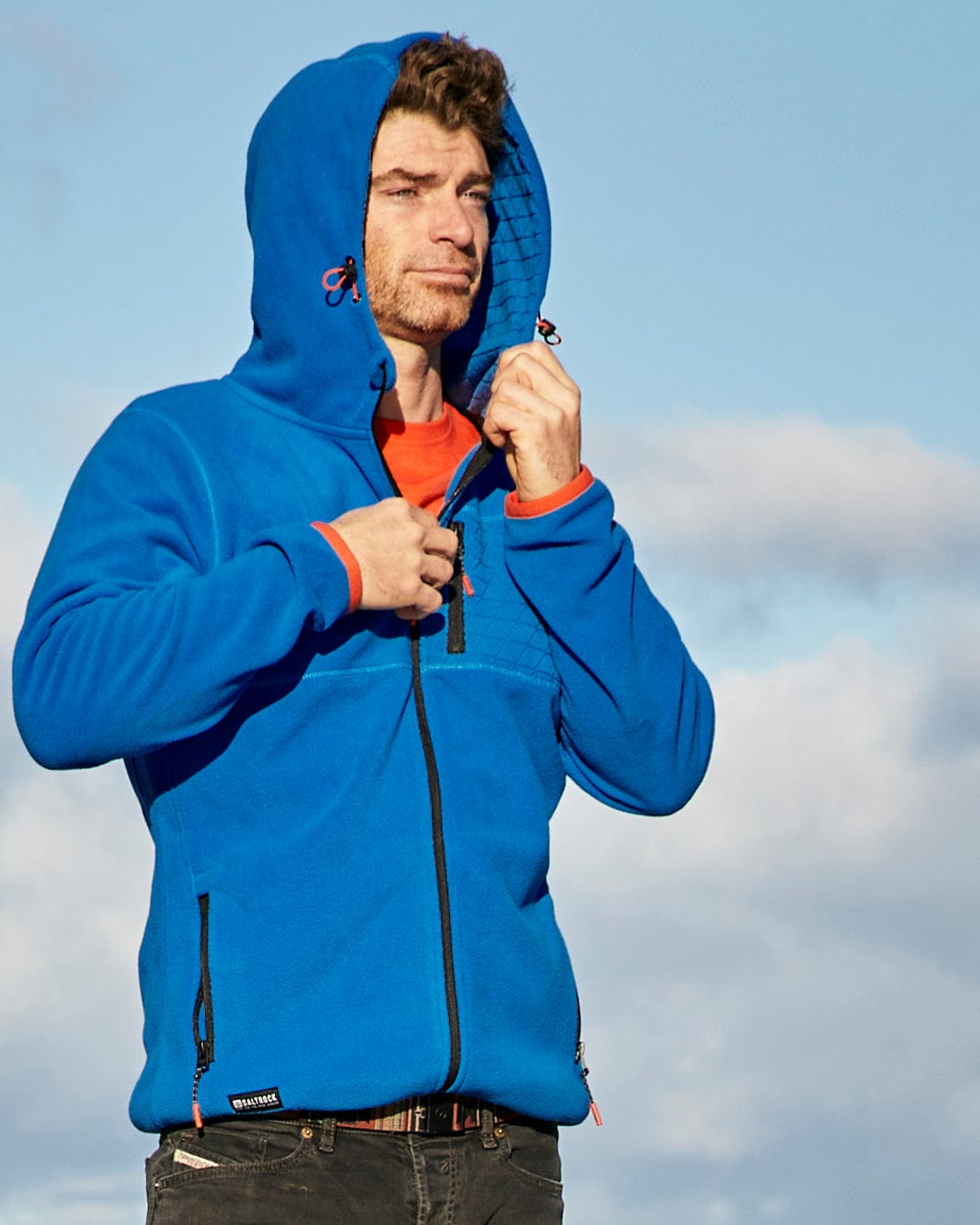 A man wearing a Senja - Mens Fleece Hoodie - Blue featuring Saltrock branding.