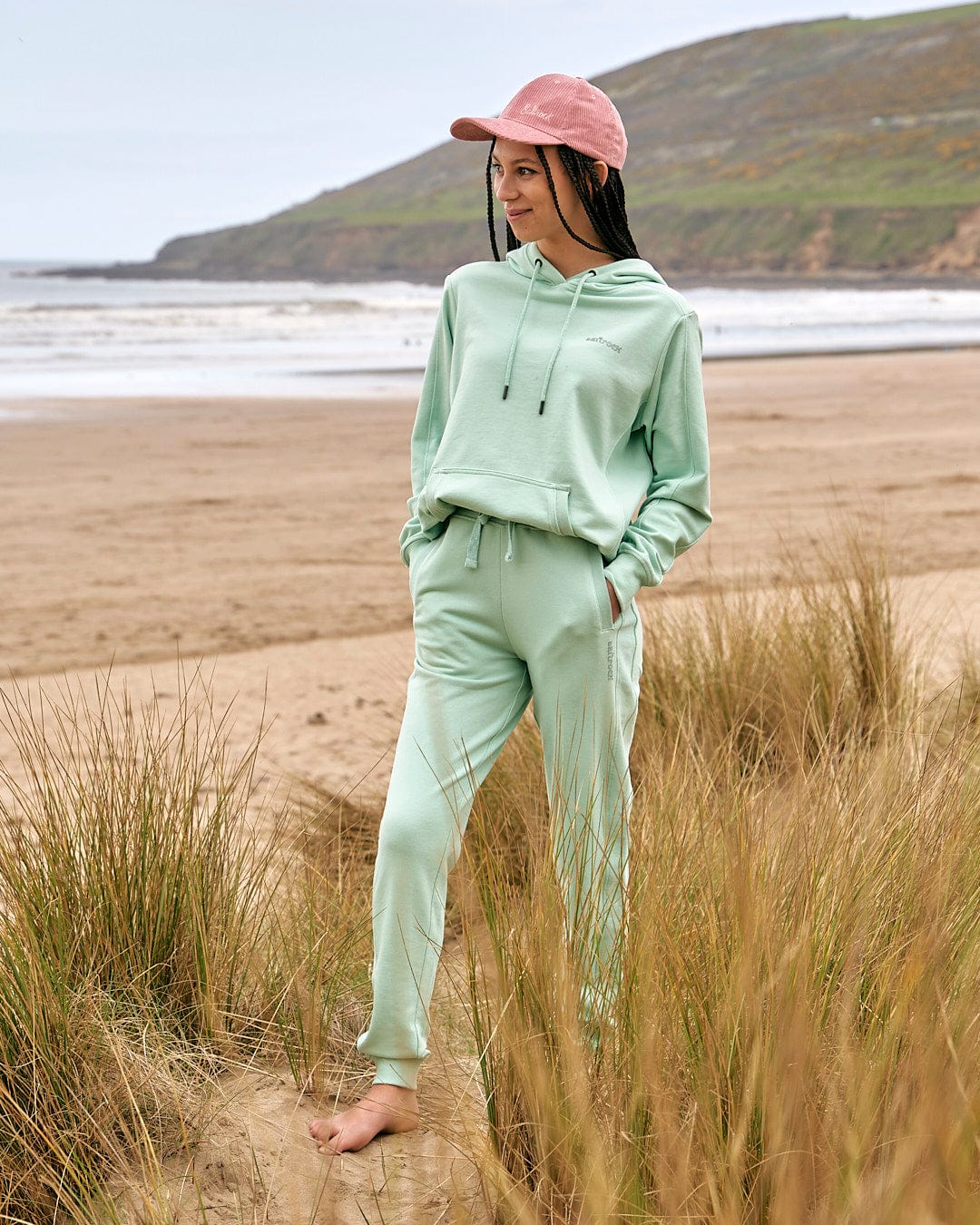 A woman wearing a Saltrock mint green hoodie and Shelley Womens Jogger - Light Green on the beach.