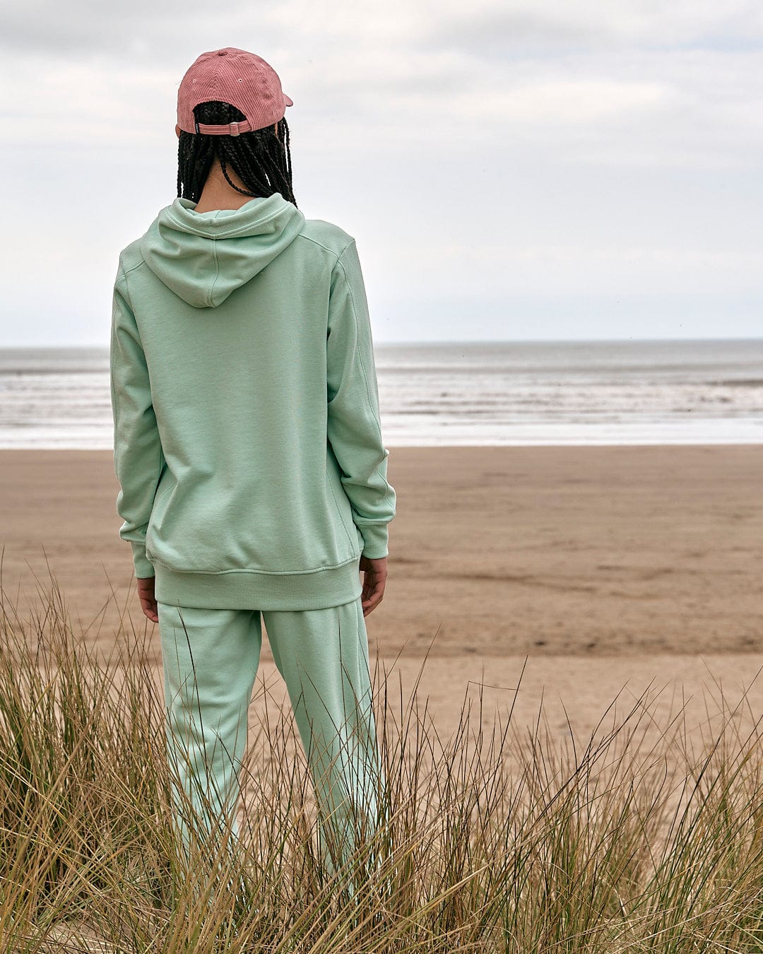 A person standing on a beach looking at the ocean wearing Shelley - Womens Jogger - Light Green by Saltrock.