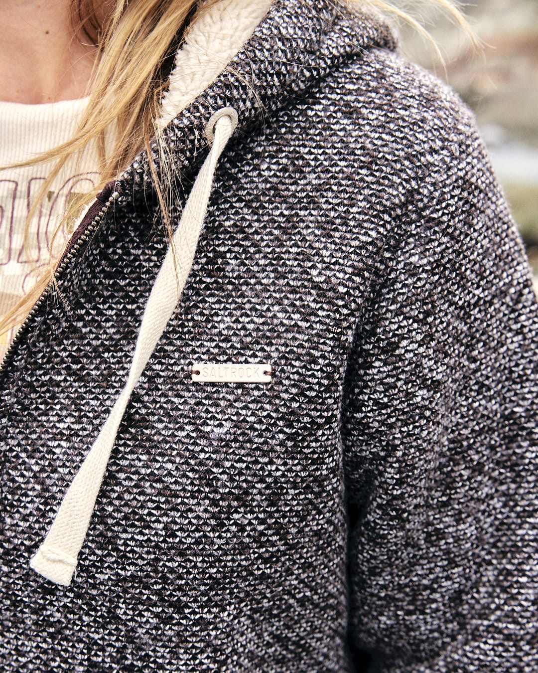 Sofie is sporting a grey hoodie with a textured knit fabric, completing her look with a hat and Saltrock Womens Borg Lined Zip Hoodie in Brown and a Saltrock badge.
