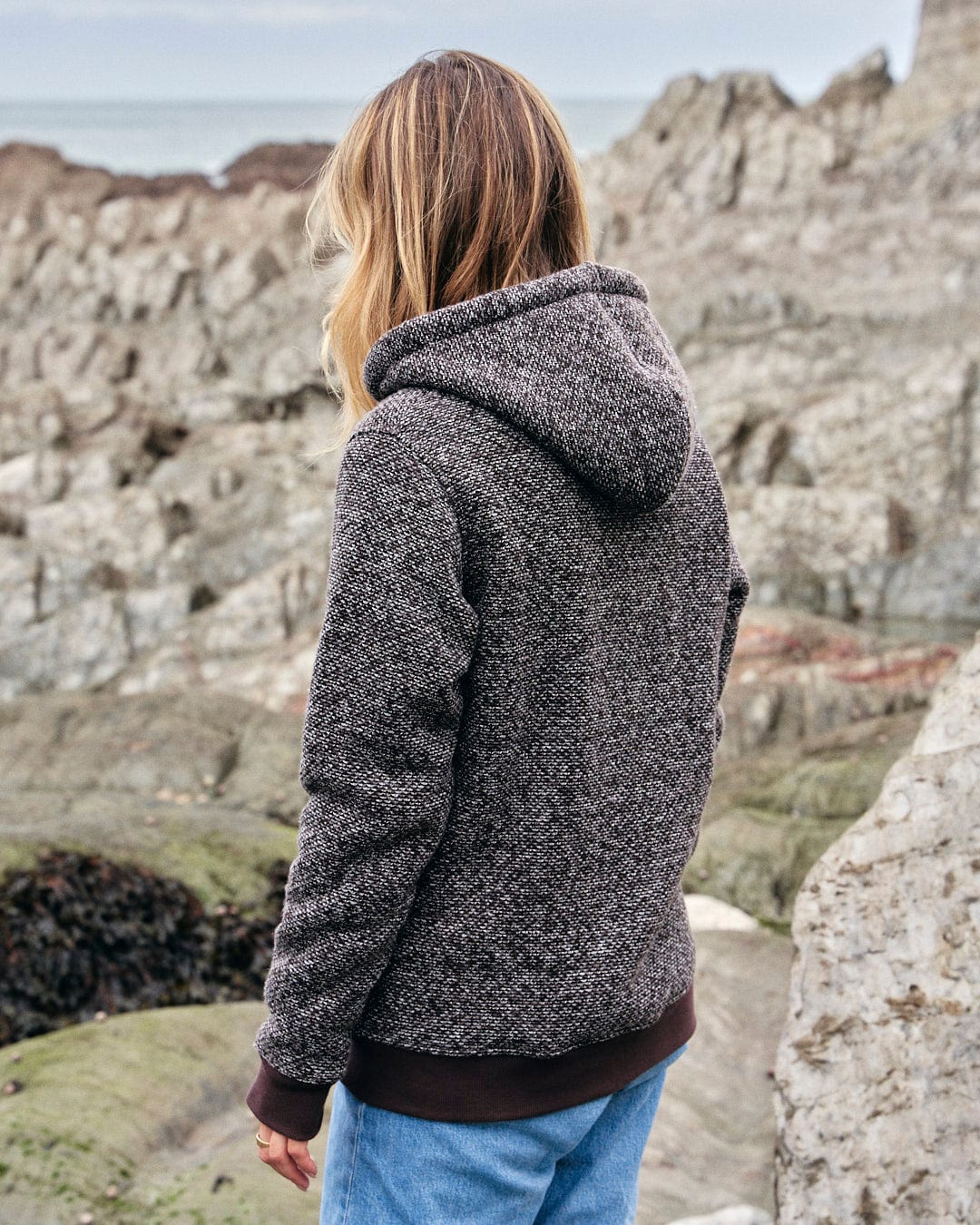 Sofie - Womens Borg Lined Zip Hoodie - Brown, a cozy choice, wearing a hoodie and looking at the ocean. (Brand name: Saltrock)