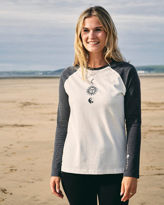 A woman is standing on the beach wearing a Saltrock t-shirt featuring crew neck design, adorned with Solstice branding.