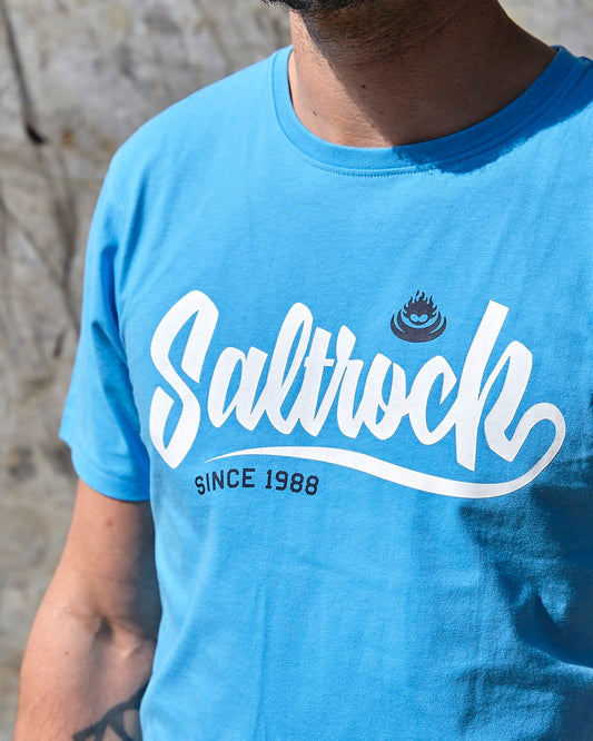 A man wearing a Saltrock Speed - Mens Short Sleeve T-Shirt - Blue with the word saltrock on it.