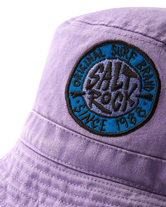 Close-up of a purple SR Original - Bucket Hat featuring an embroidered circular Saltrock badge with the words "salt rock" in turquoise.
