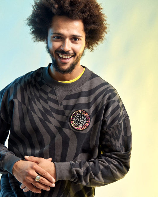 A man with curly hair stands against a gradient background, wearing an SR Warp Men's Oversized Sweat in grey by Saltrock.