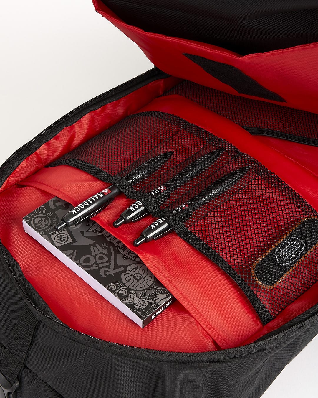 A red and black Streamline backpack from Saltrock with pens and pencils inside.