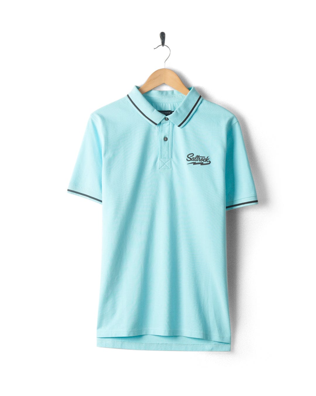 Strike Logo - Mens Short Sleeve Polo Shirt - Light Blue by Saltrock with short sleeves, a collar, and three buttons, hanging on a wooden hanger. It has a small embroidered logo on the left chest.