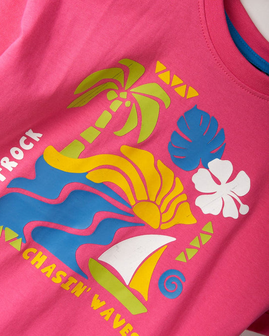 Pink t-shirt with Saltrock graphics featuring a colorful tropical print of palm trees, waves, a hibiscus flower, and a sailboat. Made from recycled materials, this cropped boxy fit design reads "CHASIN' WAVES" at the bottom. Product Name: Summer Block - Kids Recycled Cropped T-Shirt - Pink Brand Name: Saltrock