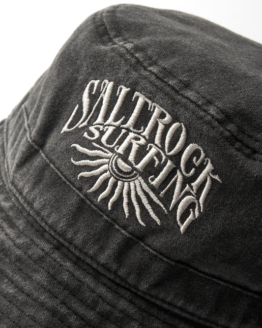 Close-up of a black Sunburst Bucket Hat - Dark Grey with "Saltrock surfing" embroidered in white thread.