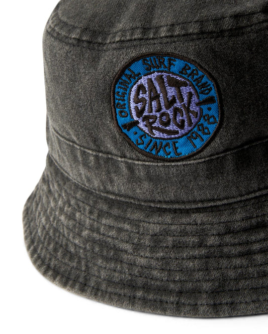 A close-up of a SR Original - Bucket Hat - Dark Grey featuring a blue circular Saltrock badge with surf branding embroidery and ventilation.