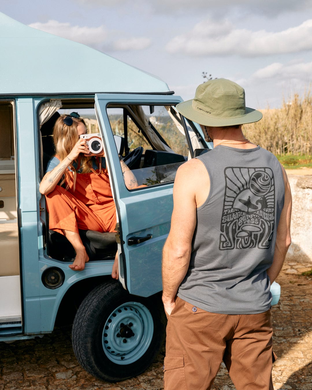 A man and a woman standing next to a blue van with Surf Fest - Mens Vest - Dark Grey from Saltrock print.