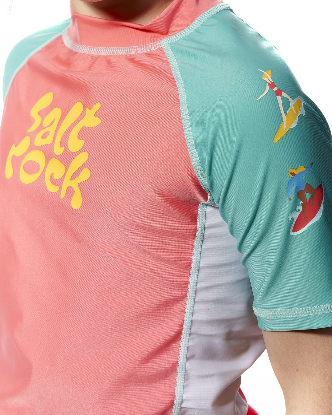 A young girl wearing a Saltrock Surf Sister - Kids Short Sleeve Rashvest in Coral/Turquoise.