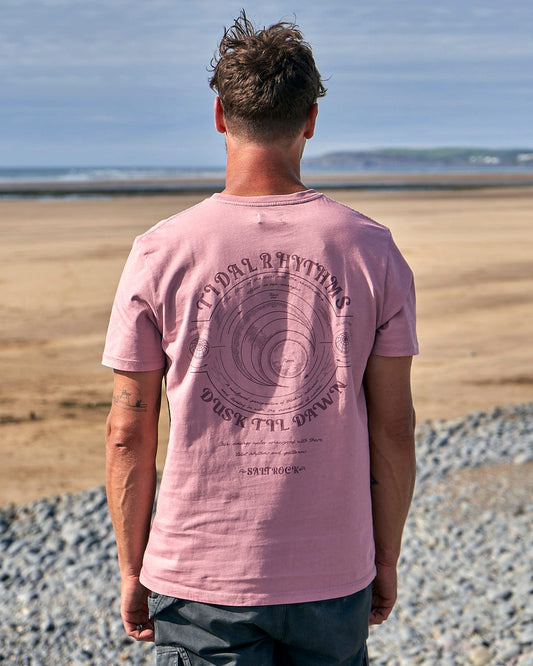 The back of a man standing on the beach wearing a Saltrock Tidal Rhythms - Mens Short Sleeve T-Shirt - Pink.