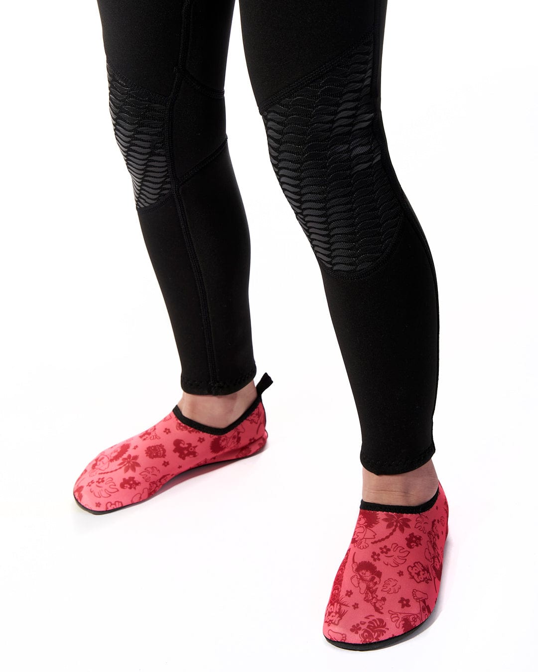 A woman wearing black and red Saltrock Core - Kids 3/2 Full Wetsuit - Red slippers.