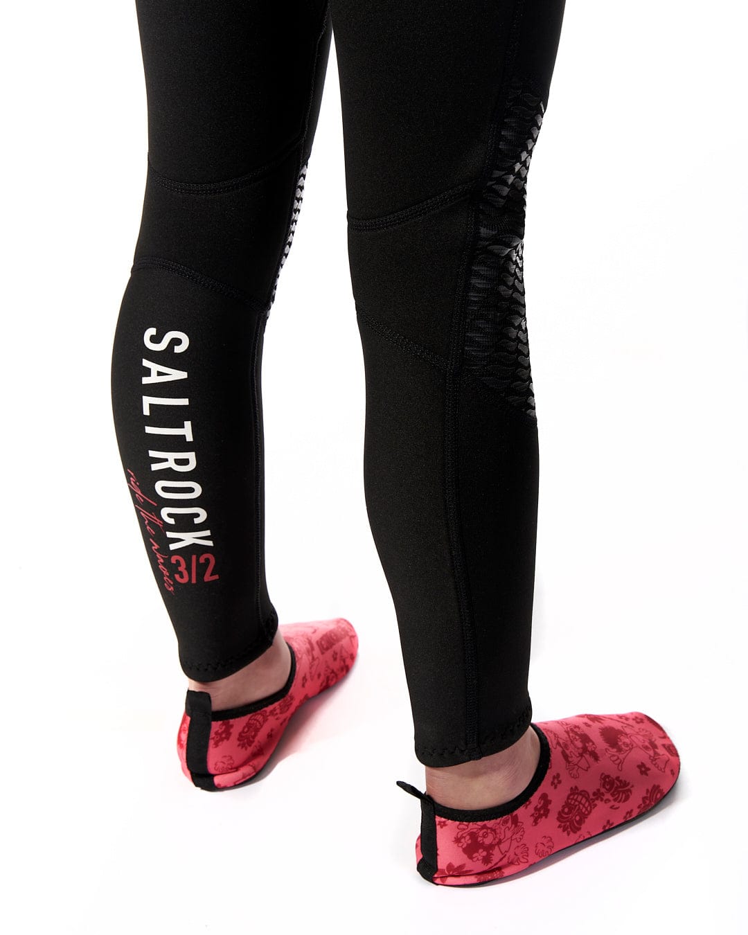 A woman wearing a pair of black and red Saltrock Core - Kids 3/2 Full Wetsuits.