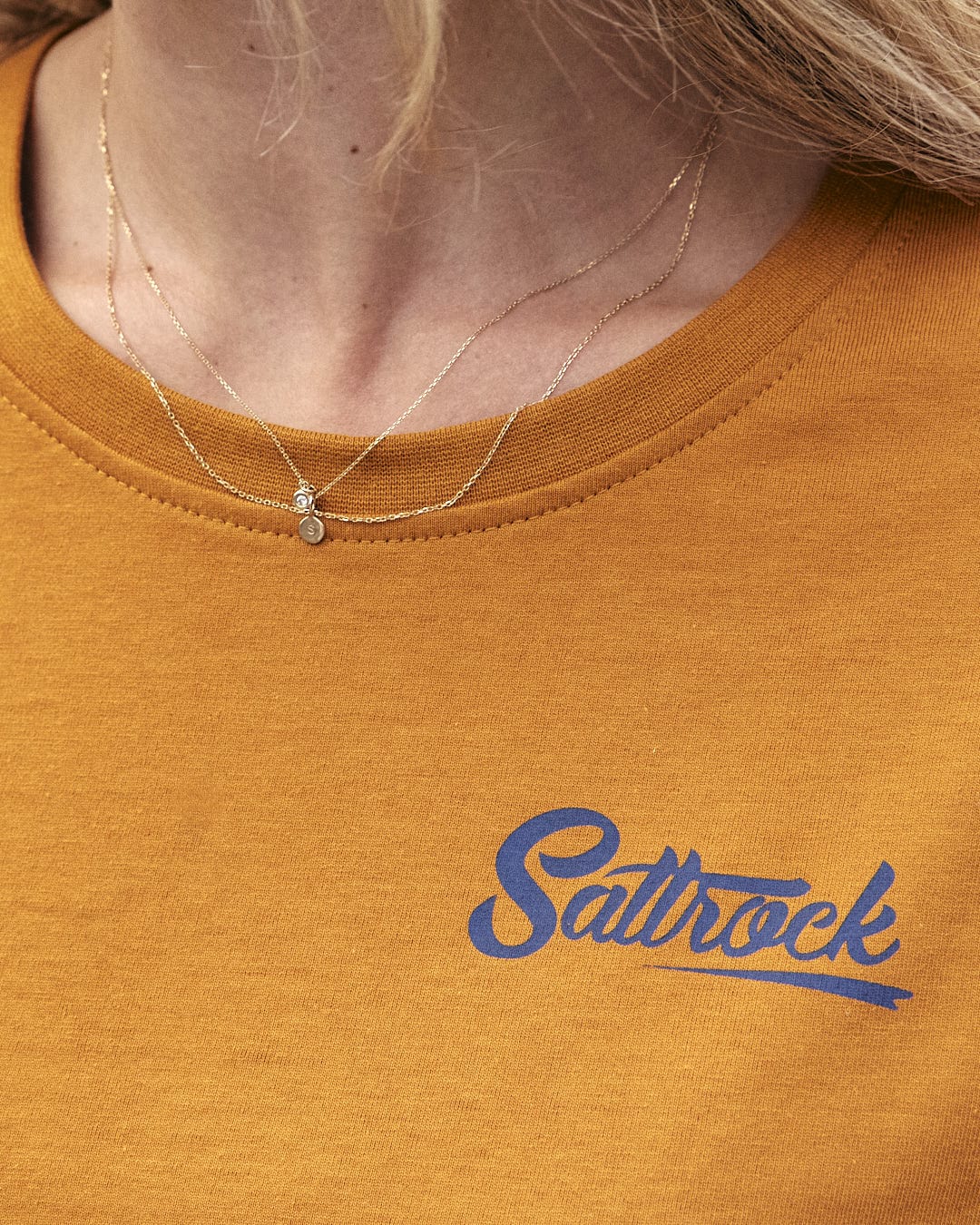 A woman wearing a lightweight fabric yellow t-shirt with the Saltrock branding.