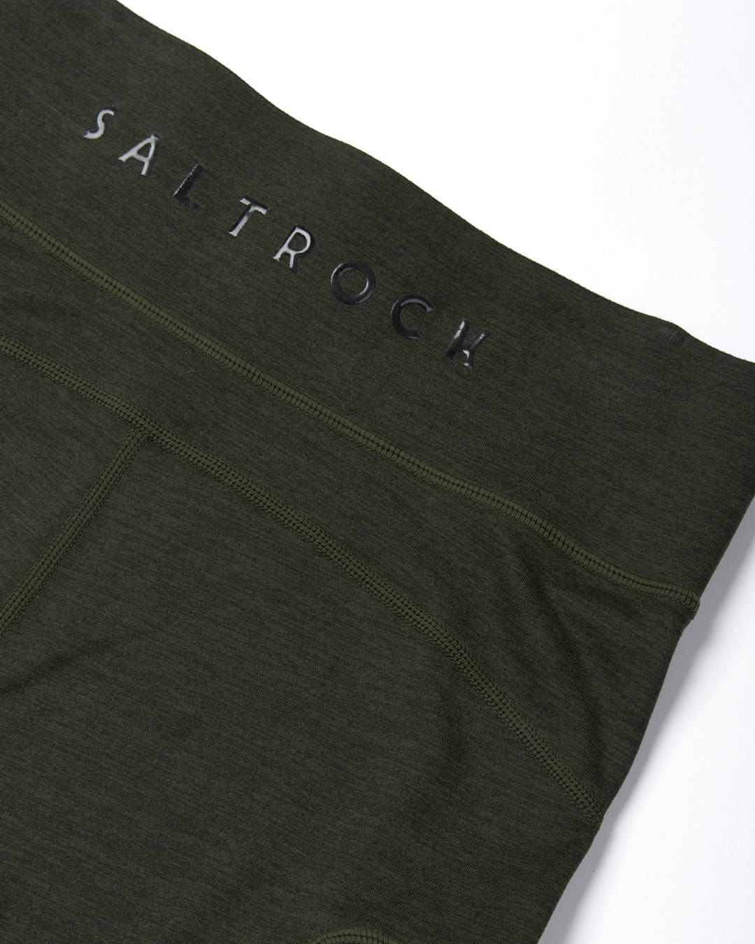 Close-up view of a high-quality stretch dark green Saltrock Trek Womens Active Leggings showing the brand name embroidered in black on the waistband.