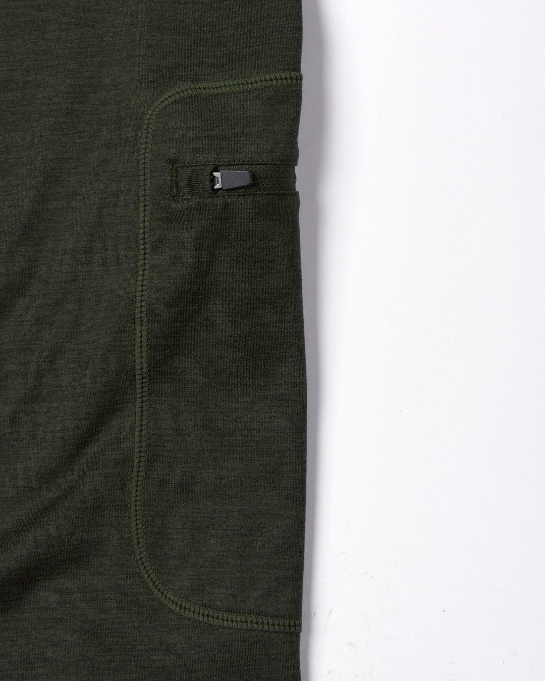 Close-up view of a Saltrock Trek - Womens Active Leggings - Dark Green with a detailed focus on a small, black zipper pocket on the side thigh.