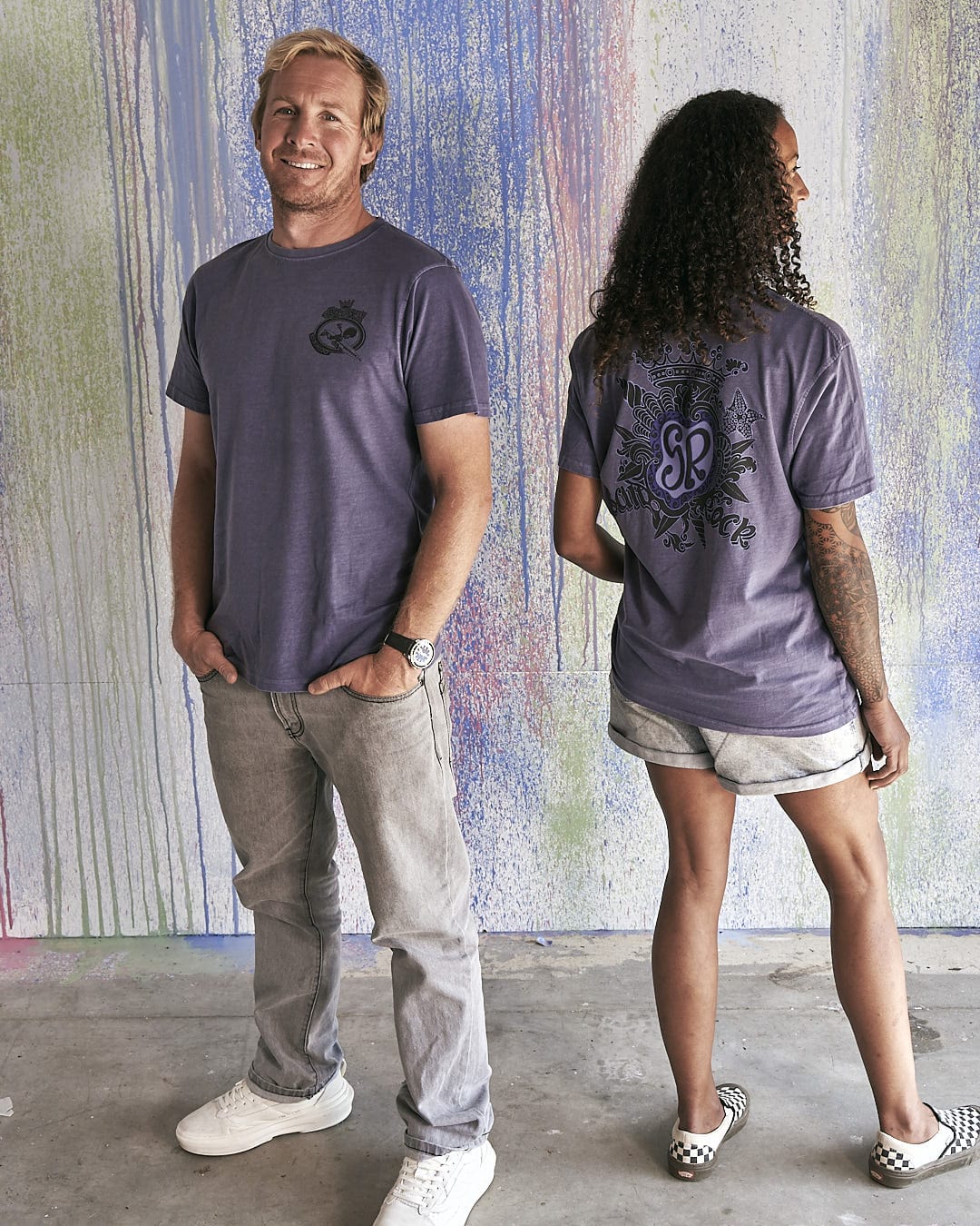 A man and woman standing next to each other wearing Saltrock's Tribal Saltrock - Limited Edition 35 Years T-Shirts.
