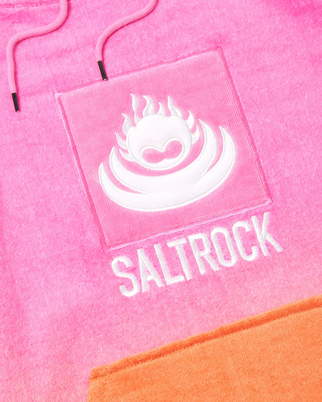 Close-up of a Saltrock pink saltrock hoodie with an embroidered logo featuring a flaming heart design above the brand name, made from 100% cotton.