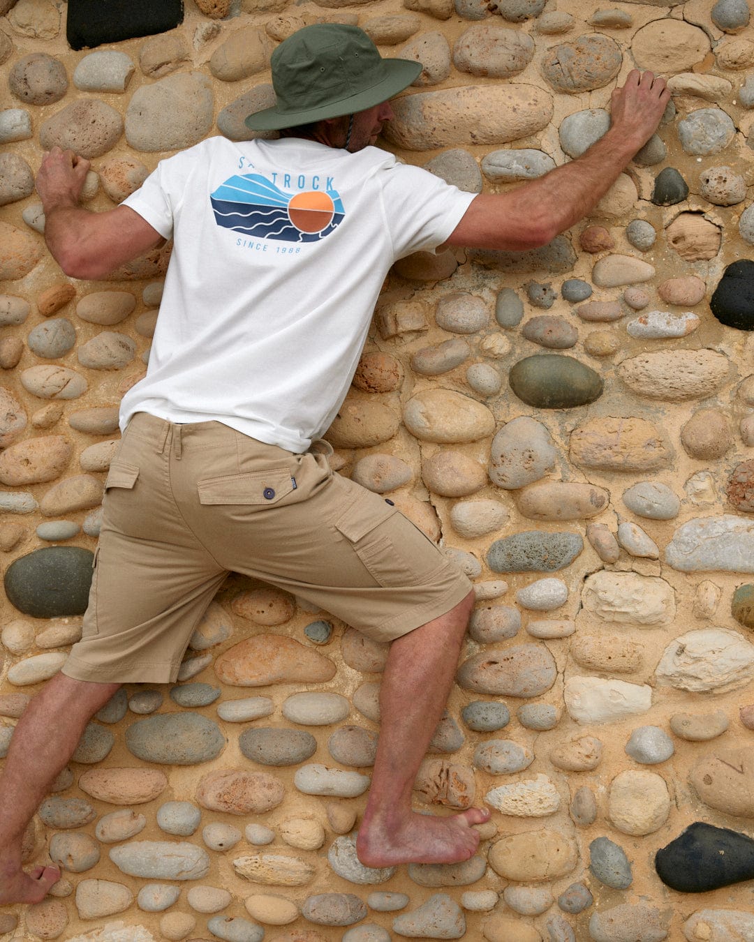 A man leaning against a rock wall with Saltrock's Vantage Colour - Mens Short Sleeve T-Shirt in White.
