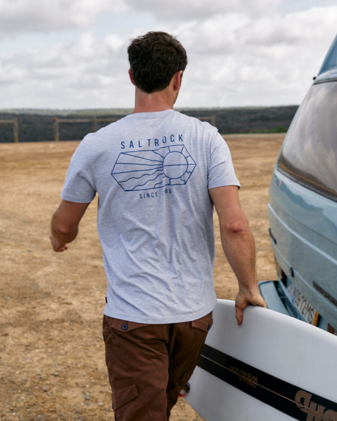 A man walking with a Vantage Outline - Mens Short Sleeve T-Shirt - Grey Marl in front of a van, showcasing the Saltrock branding.