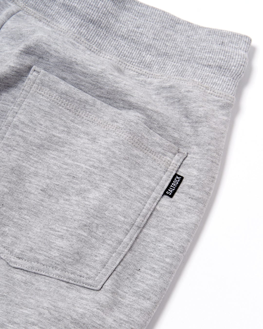 Close-up of a grey Velator womens joggers fabric texture with a pocket and Saltrock branding.