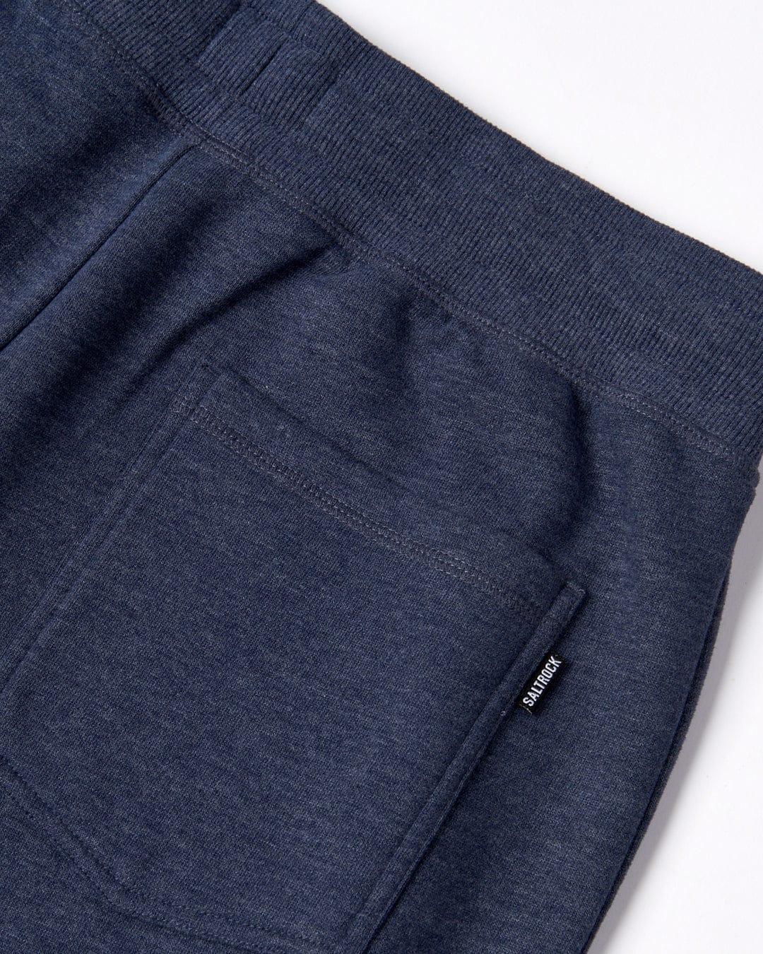 Close-up of a navy blue Velator joggers with an elasticated waistband, cuffed ankles, and a small label featuring Saltrock branding.