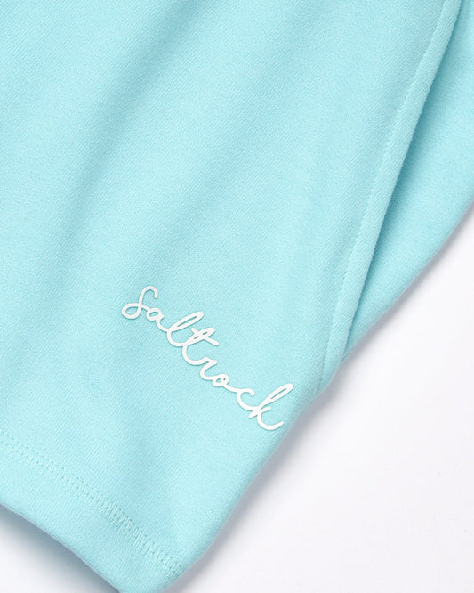 Close-up of a Velator - Womens Short - Light Blue jersey material with the word "Saltrock" embroidered in white cursive text on the lower edge.