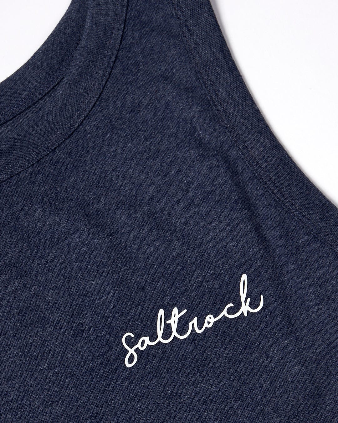 Close-up of a dark blue Velator tank top with a white woven label "Saltrock" on the chest.