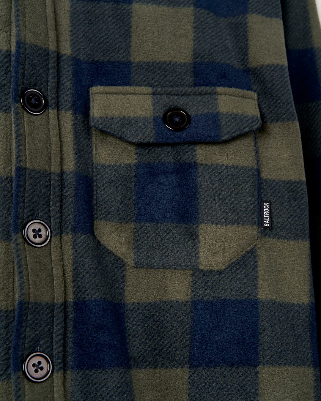 Close-up of a Waldron - Mens Fleece Shirt - Dark Green flannel shirt from Saltrock with a pocket and buttons, featuring a small logo tag on the pocket.