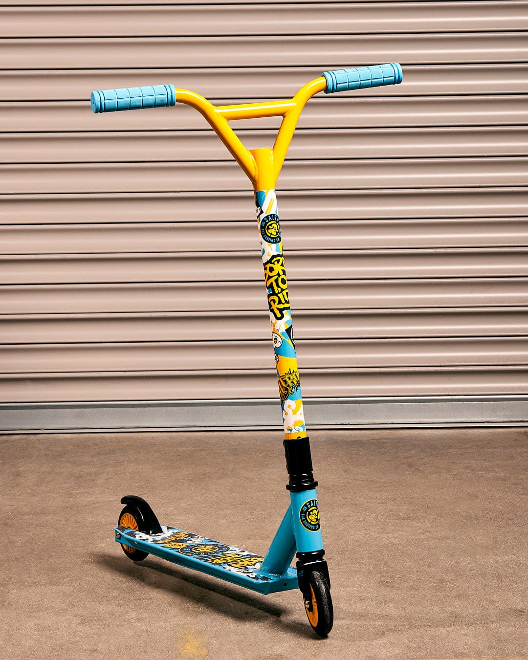 A Saltrock Warped - Stunt Scooter - Blue in front of a garage.